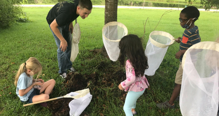 Adult helping youth catch insects with nets