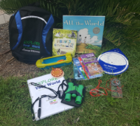 Explore Your World backpack kit with activities and books on grass