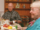 an elderly man and woman share a full meal at a home table