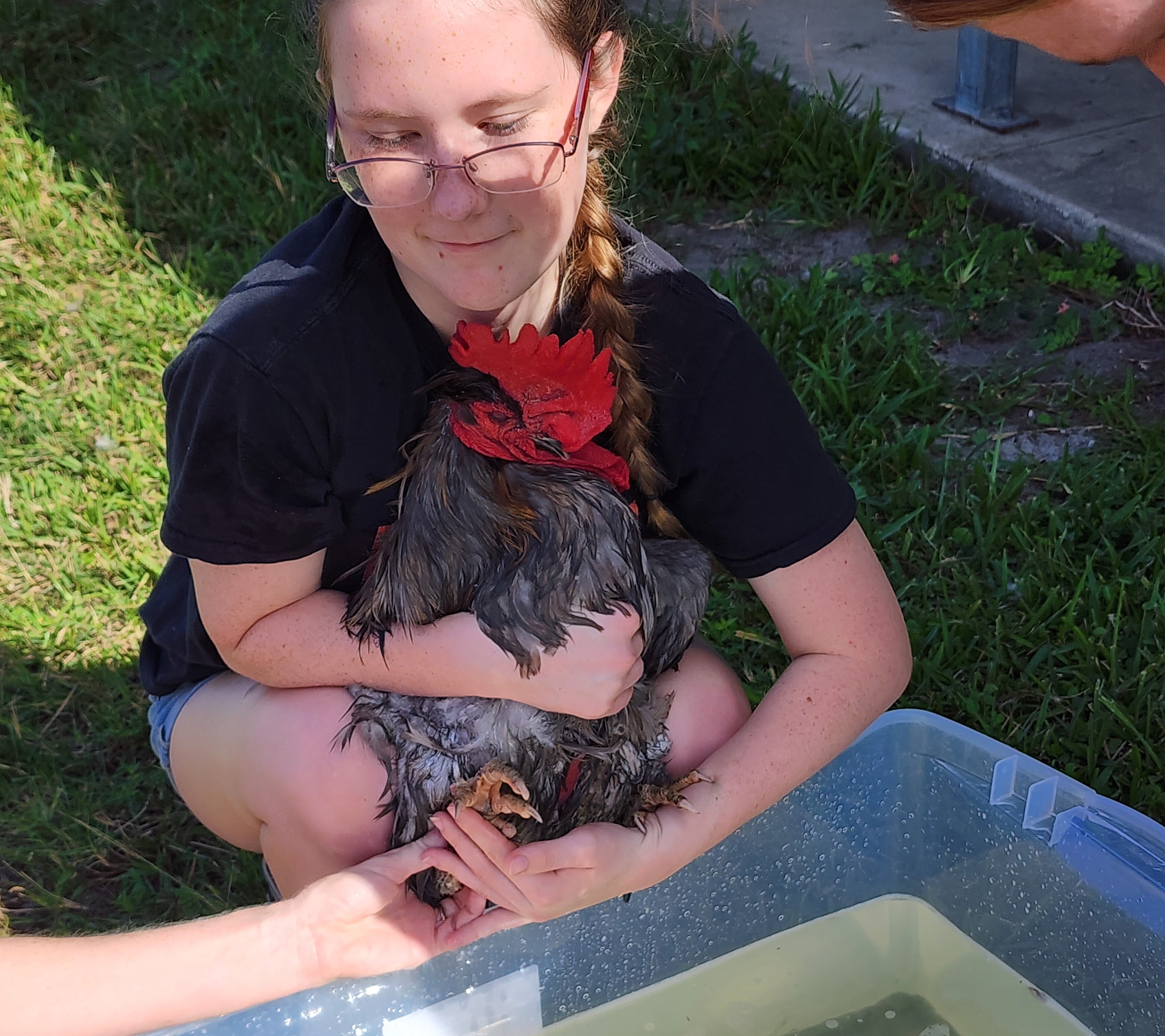 A girl holding a chicken beside bath water