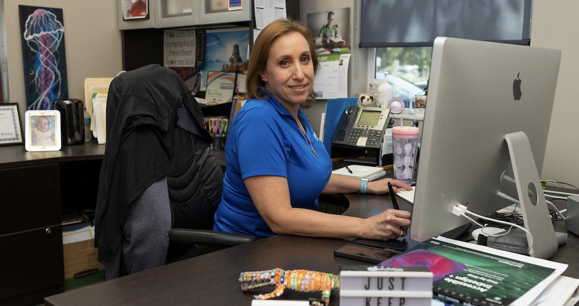 A woman sitting at a desk with an iMac