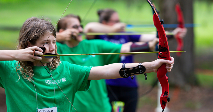 4-H students and instructors at an archery range..