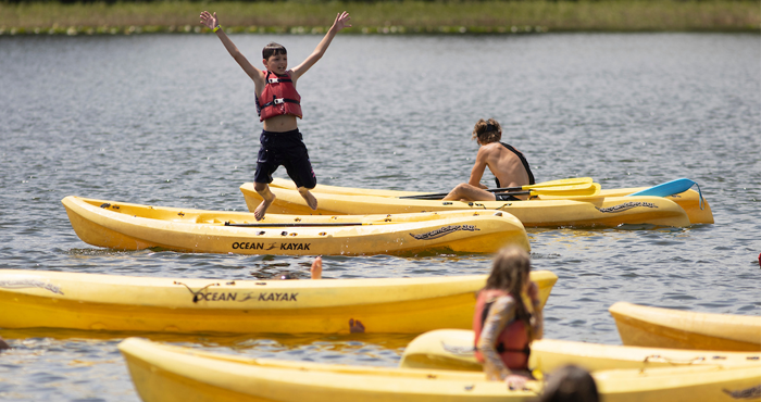 4-H kids in canoes on a lake, one midair after a jump.