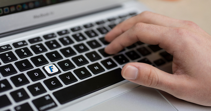 A closeup of a hand typing on a laptop.