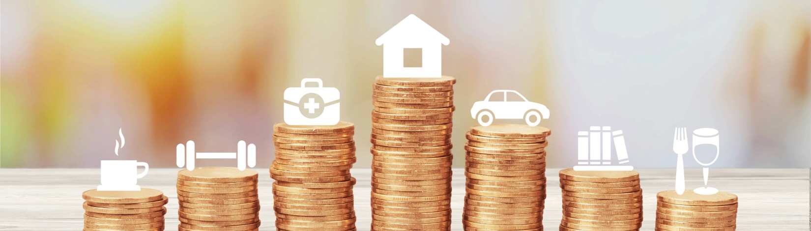 Seven stacks of coins on a table form a bar‑chart shape; each stack is topped with a white icon—coffee cup, dumbbell, medical bag, house (tallest), car, books, and dining—representing budgeting categories.