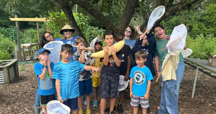 Group of youth making silly faces and holding insect nets as they pose for a group photo