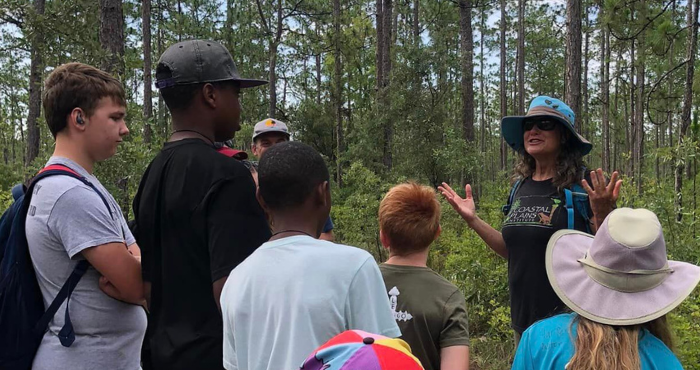 Woman teaching a group of children in a long-leaf pine forest