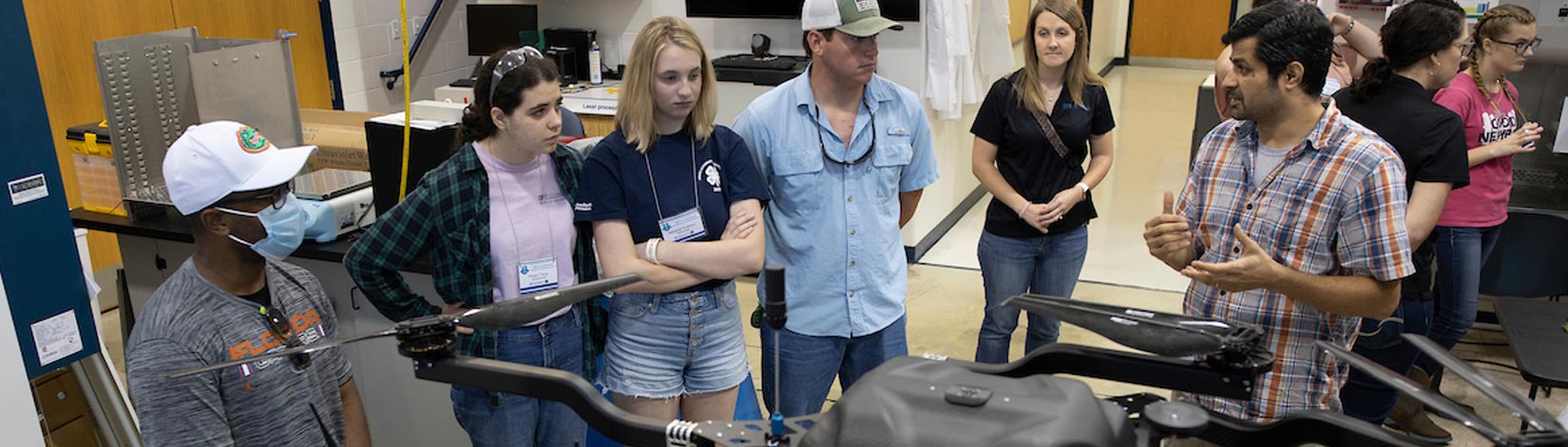 A group of 4-H students in a lab with a large drone.