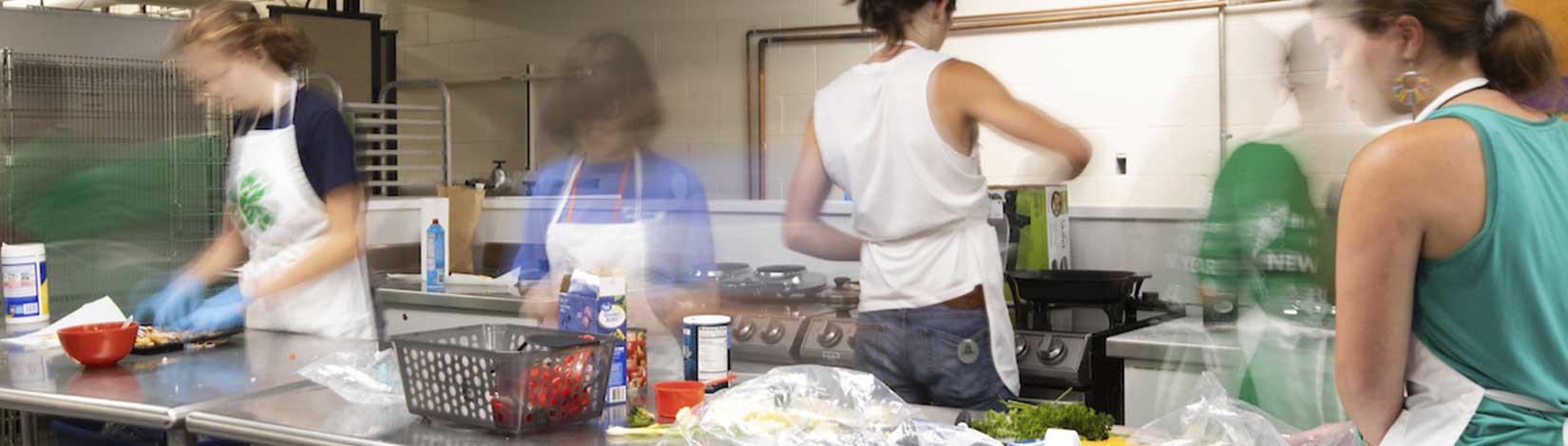 A group of 4-H teens preparing food in an industrial kitchen.