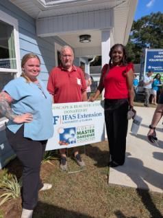 new homeowners posting by sign with volunteer