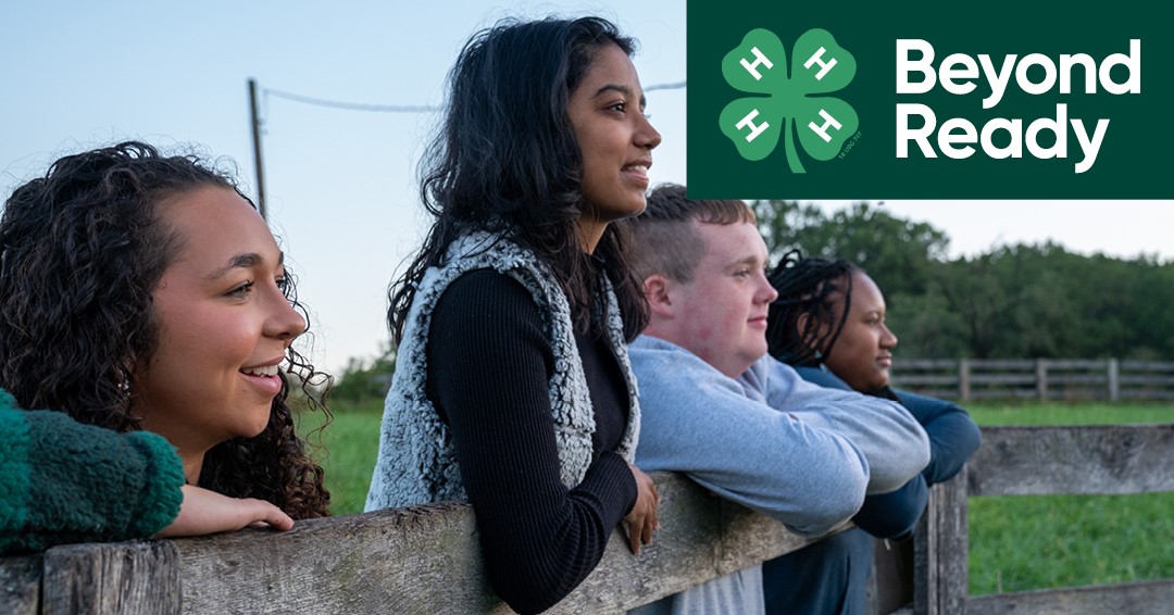 four young people leaning forward on a fence, gazing into the unknown