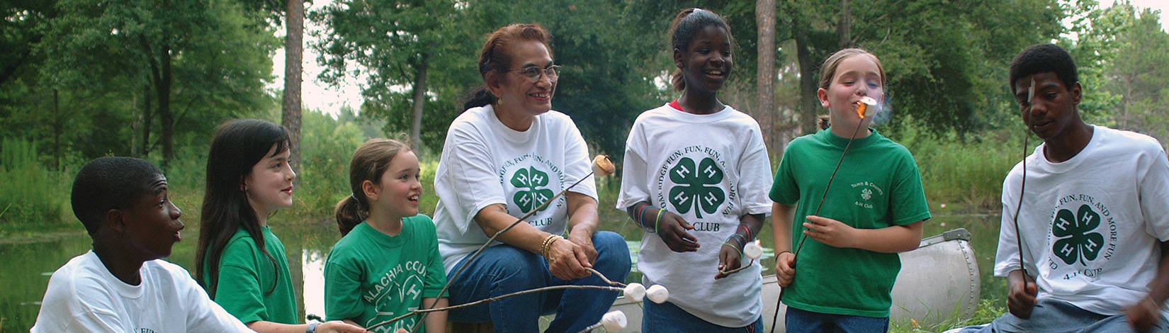 A group of Florida 4-H Youth roast marshmallows around a campfire