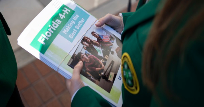 4-H Youth wearing 4-H Jacket holding a book