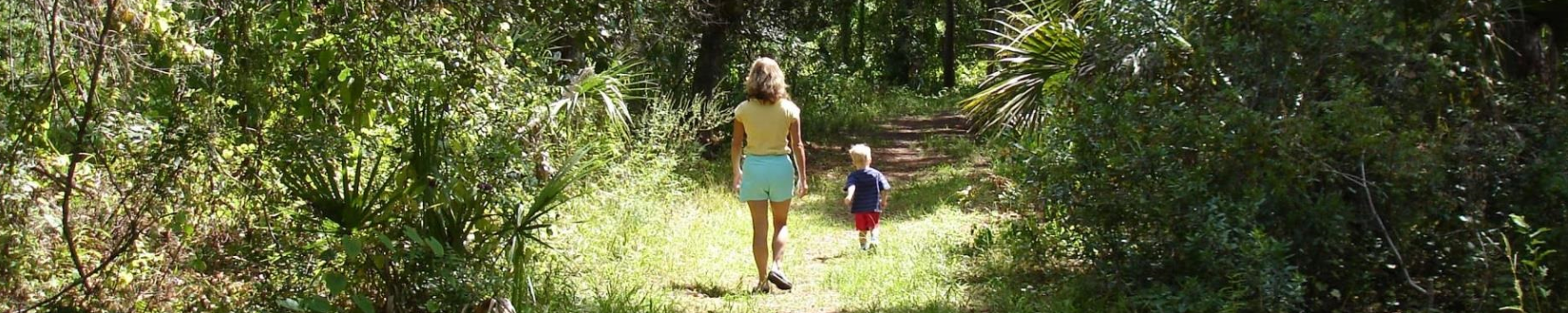 A woman and young child walk along a dirt trail through Red Bug Slough Preserve in Sarasota County