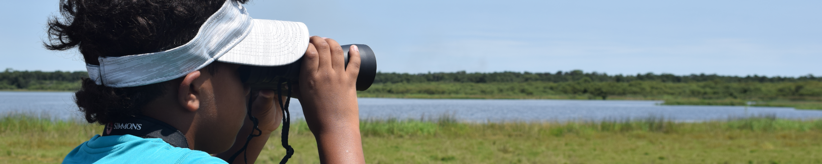 a participant at a 4-h youth summer camp uses binoculars to scan for wildlife and scenery at a local state park. [credit: uf/fias extension sarasota county]