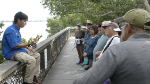 staff and students stop on a bay-fronting boardwalk to discuss mangroves and coastal resources