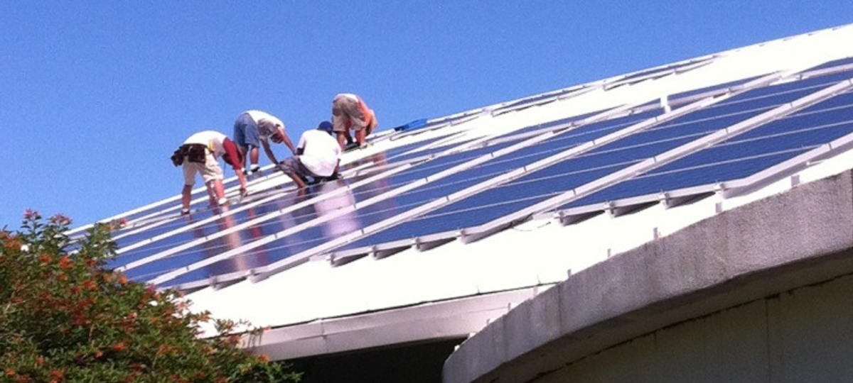 workers install solar panels on the roof of the sarasota county extension office