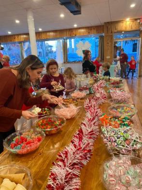 group of kids and parents picking out candy to put on their gingerbread house. 