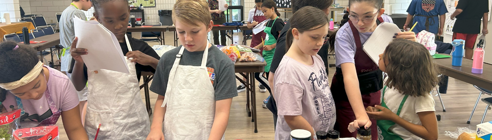 children with aprons looking at recipes
